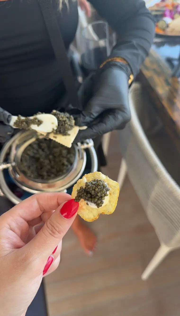 Caviar served on a crisp, the tin held behind by a gloved attendant